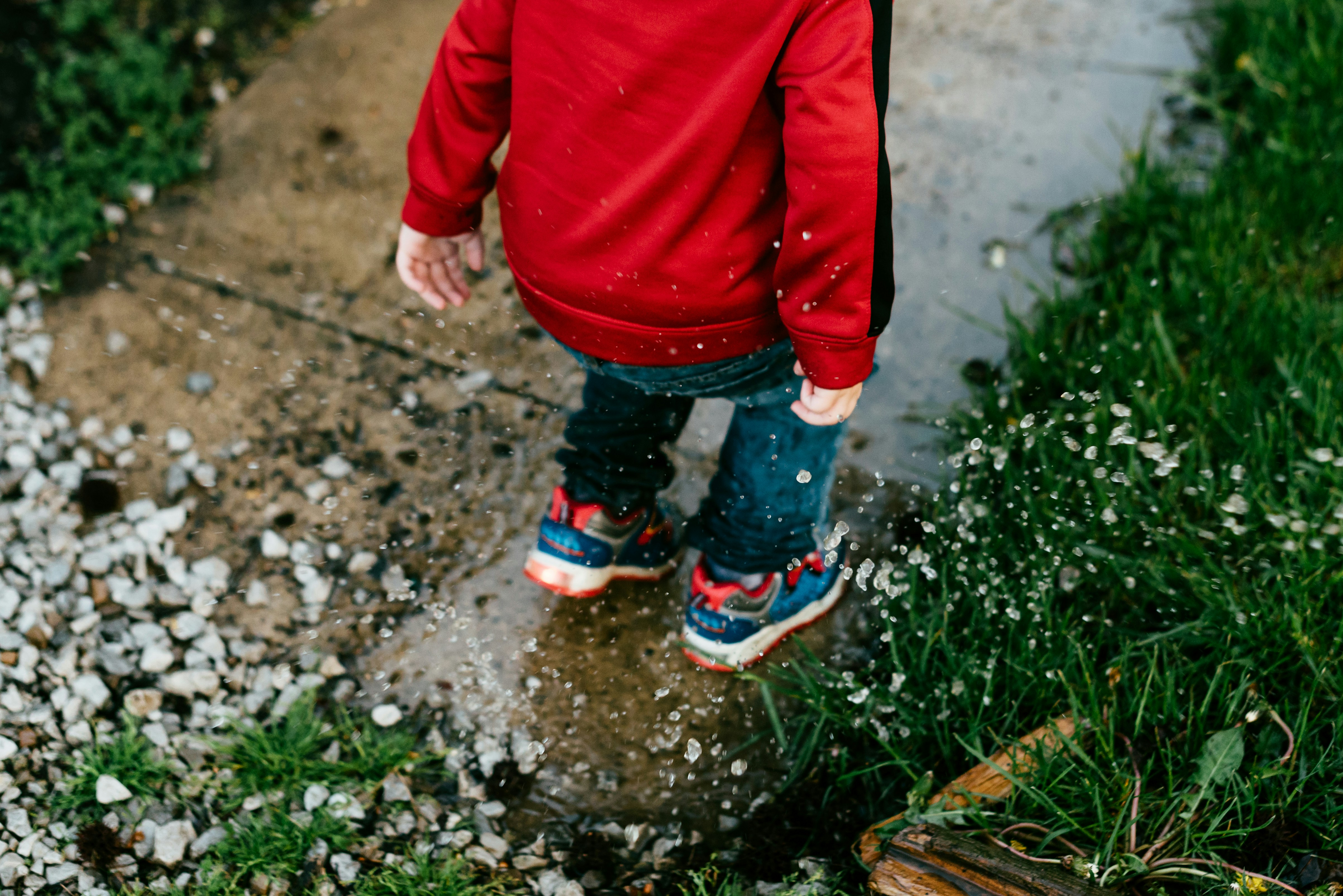 child splashing in puddle