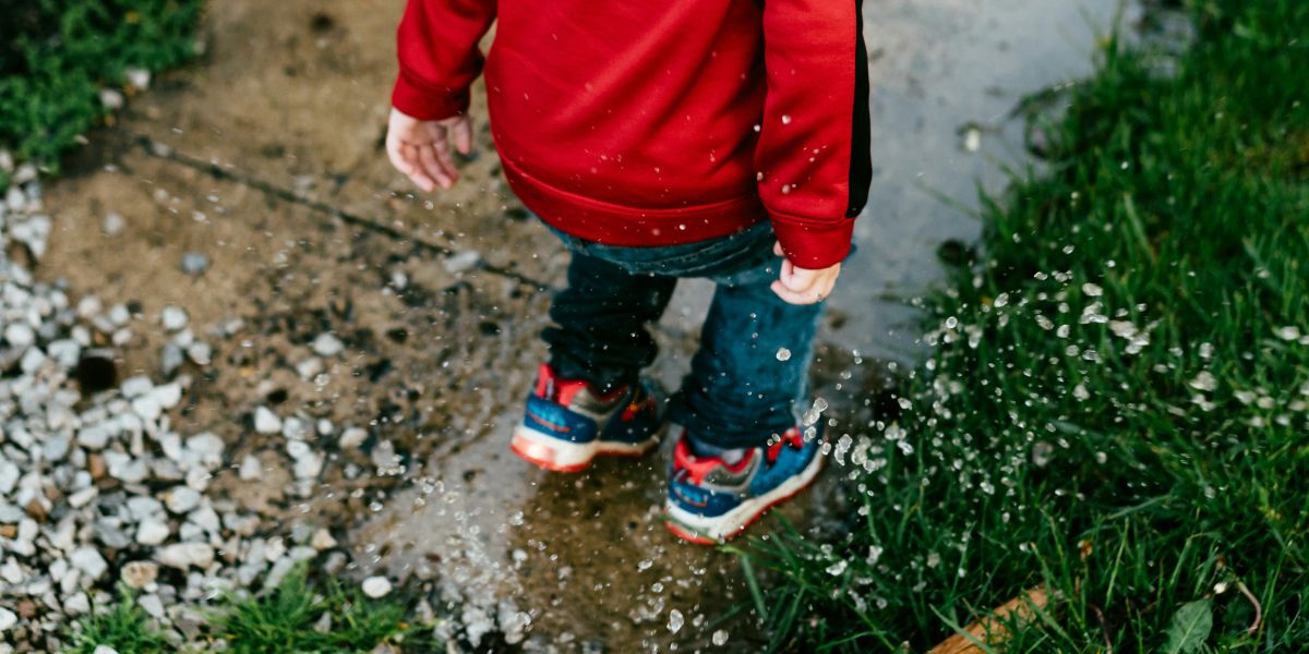 child splashing in puddle